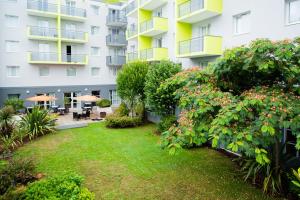 un edificio de apartamentos con un patio con plantas y flores en Zenitude Hôtel-Résidences Les Portes de l'Océan, en Saint-Nazaire