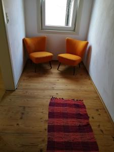 dwa pomarańczowe krzesła siedzące w korytarzu z dywanem w obiekcie Ferienwohnung Burg Lindenfels w mieście Lindenfels