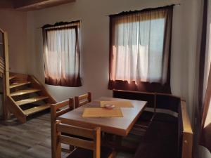 a dining room with a table and chairs and windows at Luna in Prokuplje