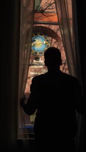 a man standing in front of a window with a clock at Five Stars Bed&Breakfast in Wrocław