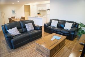 a living room with two leather couches and a coffee table at Longreach at Port Elliot in Port Elliot