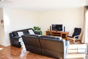 a living room with two leather couches and a television at Longreach at Port Elliot in Port Elliot