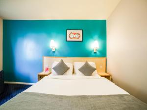 a bedroom with a large bed with a blue wall at OYO Sunrise Hotel, A46 N Leicester in Thrussington