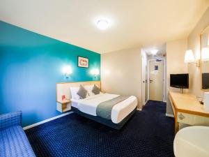 a hotel room with a bed and a desk at OYO Sunrise Hotel, A46 N Leicester in Thrussington