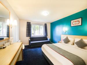 a hotel room with a bed and a chair at OYO Sunrise Hotel, A46 N Leicester in Thrussington