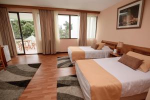 a hotel room with two beds and a balcony at Hotel del Valle Azapa in Arica