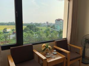 a table and chairs in a room with a large window at Dragon Airport Hotel in Noi Bai