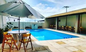 a table with an umbrella next to a swimming pool at Hotel Brisa do Aracati in Aracati
