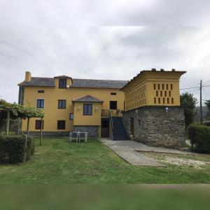 a large yellow house with a stone wall at Apartamentos El Campo in Castropol