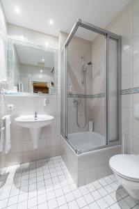 a bathroom with a shower and a sink and a toilet at Galerie Hotel Leipziger Hof in Leipzig