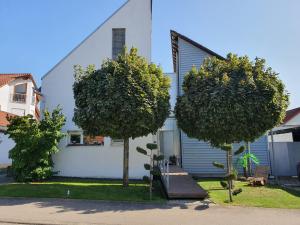 une maison blanche avec des arbres devant elle dans l'établissement Ferienwohnung Schwartz, à Singen