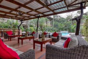 un patio al aire libre con sofás, mesas y una piscina en Forest Lodge, en St Lucia