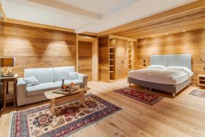 ein Schlafzimmer mit einem Bett, einem Sofa und einem Tisch in der Unterkunft Hotel Villa Alpina ***S in Cortina d'Ampezzo