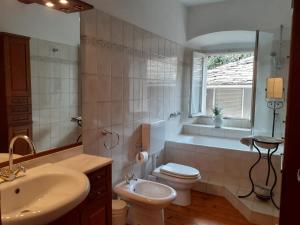 een badkamer met een toilet, een bad en een wastafel bij Attico sul Fiume in Varallo
