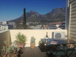 Cape Town的住宿－自由小屋住宿加早餐旅館，阳台配有桌子,种植了植物,享有山景