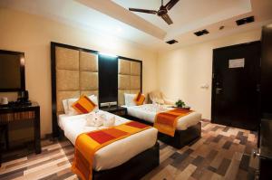 a hotel room with two beds and a television at The Oakland Plaza by Orion Hotels in New Delhi