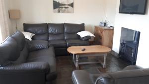 uma sala de estar com um sofá de couro e uma mesa em 12 Tullybay Drumcrow east with WIFI em Enniskillen