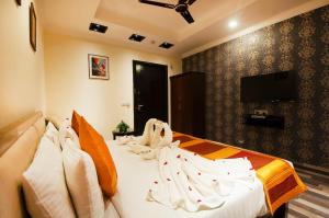 a bedroom with a bed with white sheets and a flat screen tv at The Oakland Plaza by Orion Hotels in New Delhi
