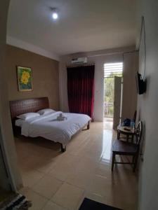 a bedroom with a bed and a table and a window at Tulip Inn Tomohon in Tomohon