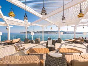 un patio con mesas, sillas y agua en Amàre Beach Hotel Ibiza - Adults Recommended, en Bahía de San Antonio