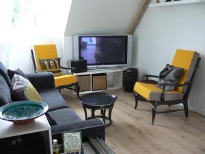 sala de estar con sofá, sillas y TV en TyNoLa en Ploudaniel
