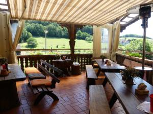 un restaurante con mesas y bancos de madera y vistas en Pension Holzerstube, en Beerfelden