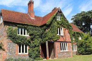 an old brick house with ivy growing on it at Church Farm B&B Suffolk in Great Welnetham