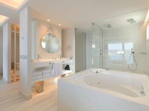 a white bath tub sitting next to a white sink at Amàre Beach Hotel Ibiza Adults Only in San Antonio Bay