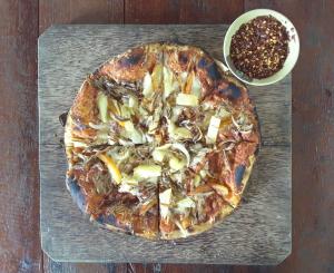 a pizza sitting on top of a wooden cutting board at Mutiara Beach Resort in Berakit