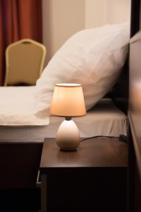 una pequeña lámpara sentada en una mesa junto a una cama en Hotel Hensch, en Łódź