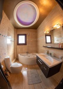 a bathroom with a tub and a toilet and a sink at Luxury Villa Thea in Volos