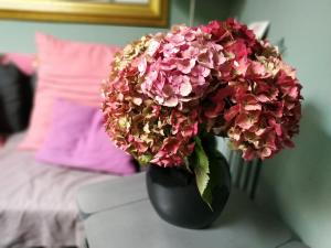 a black vase filled with pink flowers on a table at Chez Anne in Fécamp