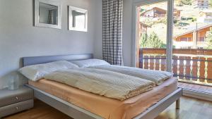 a bed in a bedroom with a large window at Château A&B in Saas-Fee