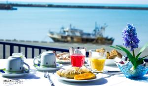 una mesa con platos de comida y vasos de zumo en Hotel Al Faro, en Licata