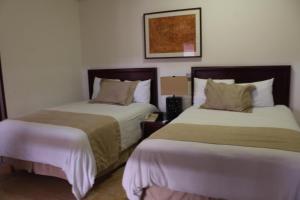 a hotel room with two beds and a picture on the wall at Hotel Casa las Mercedes in Oaxaca City