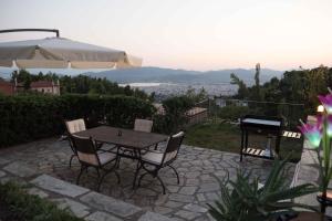 een tafel en stoelen met een parasol en een piano bij Tranquil Infinity Pool Getaway (private jacuzzi and steam bath, pool, garden, sea and city views) in Volos