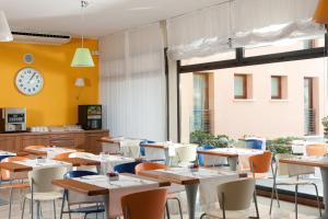 restauracja ze stołami i krzesłami oraz zegarem na ścianie w obiekcie BEST WESTERN Titian Inn Hotel Venice Airport w mieście Tessera