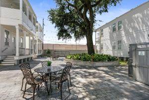 eine Terrasse mit einem Tisch, Stühlen und einem Baum in der Unterkunft Fabulous Cottages with City Views in New Orleans