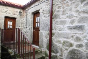 a stone house with a wooden door and stairs at Casa da Avó in Arcos de Valdevez