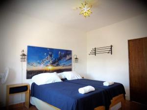 a bedroom with a blue bed with a painting on the wall at La Catrina Hostel in San Miguel de Allende