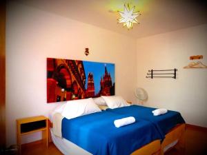 a bedroom with a blue bed with a painting on the wall at La Catrina Hostel in San Miguel de Allende