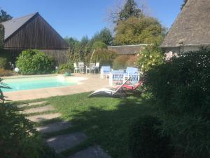 um quintal com uma piscina, uma mesa e cadeiras em Le Clos Saint-Brice em Les Portes du Coglais