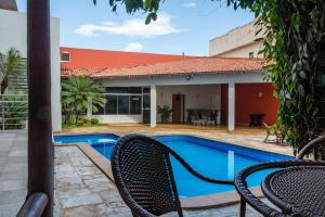 a pool with two chairs next to a house at Lindóya Hotel in Catalão