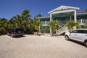 a car parked in front of a house with palm trees at Aqua Breeze Apartment in Kralendijk