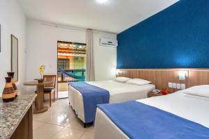 a hotel room with two beds and a blue wall at Hotel Beach Hills in Porto Seguro