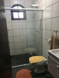 uma casa de banho com um chuveiro, um WC e uma janela. em recanto paraty mirim em Paraty