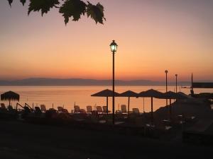 a beach with chairs and umbrellas at sunset at Eros Beach Hotel in Benitses