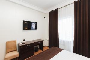 a bedroom with a bed and a desk and a television at Beluga Hotel in Atyraū
