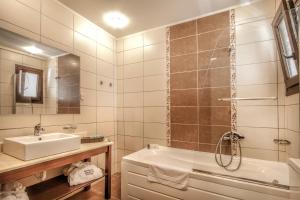 a bathroom with a sink and a tub and a mirror at Skopelos Holidays Hotel & Spa in Skopelos Town