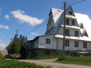 ein großes weißes Haus mit einem Dach in der Unterkunft Pokoje Gościnne Irena in Bukowina Tatrzańska